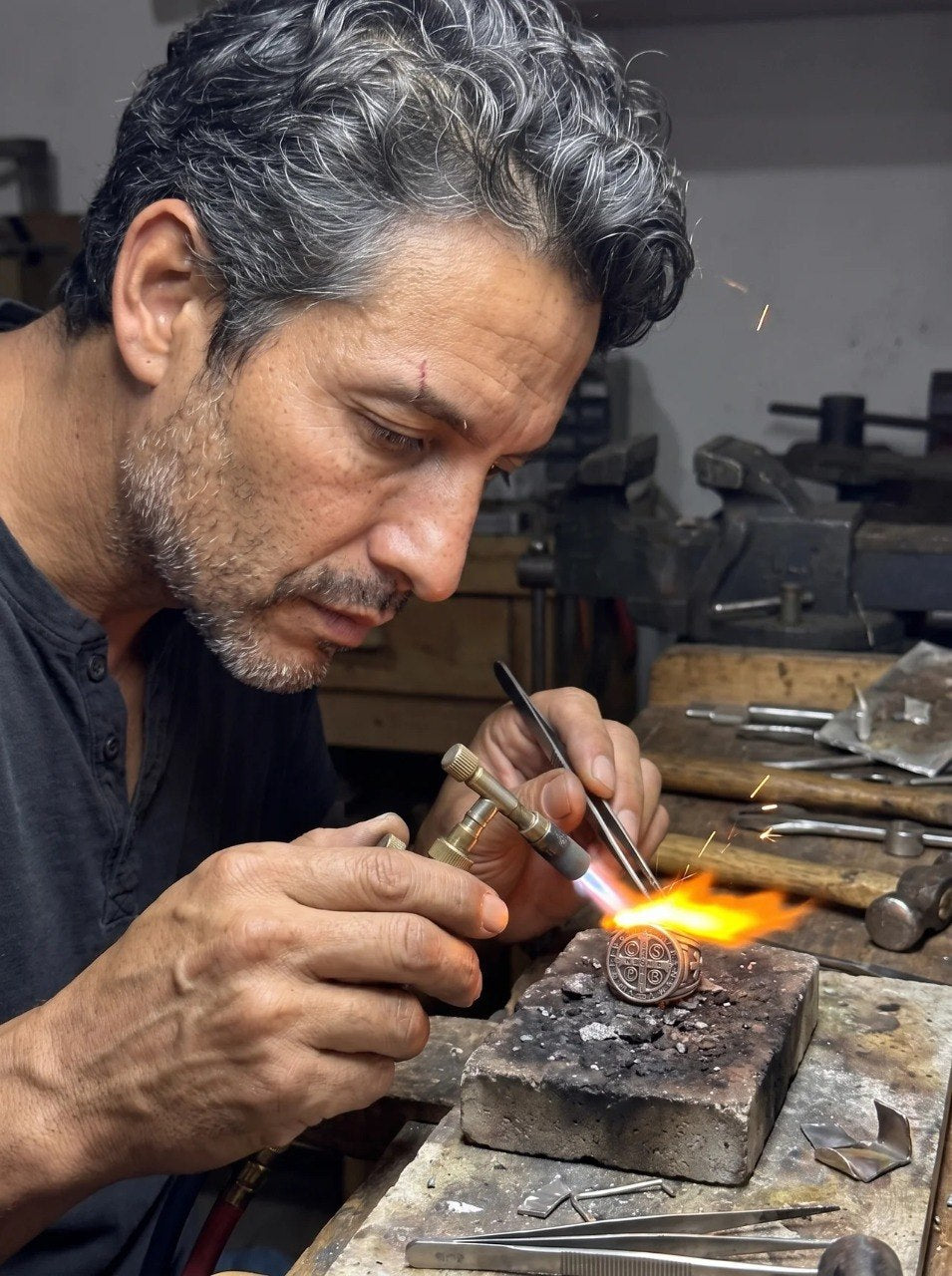 El orfebre suelda la medalla de San Benito en el taller